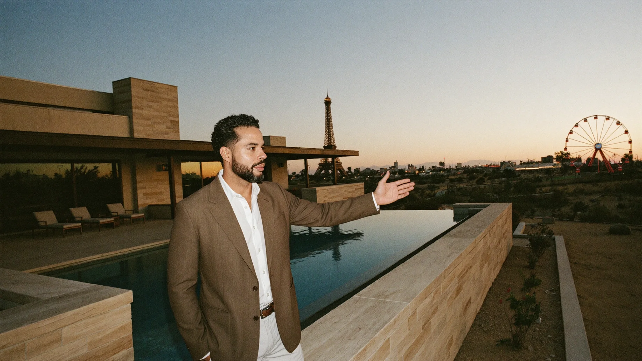 Nicholas Aponte-Rodriguez beside an infinity pool at dusk, gesturing toward the Las Vegas skyline.