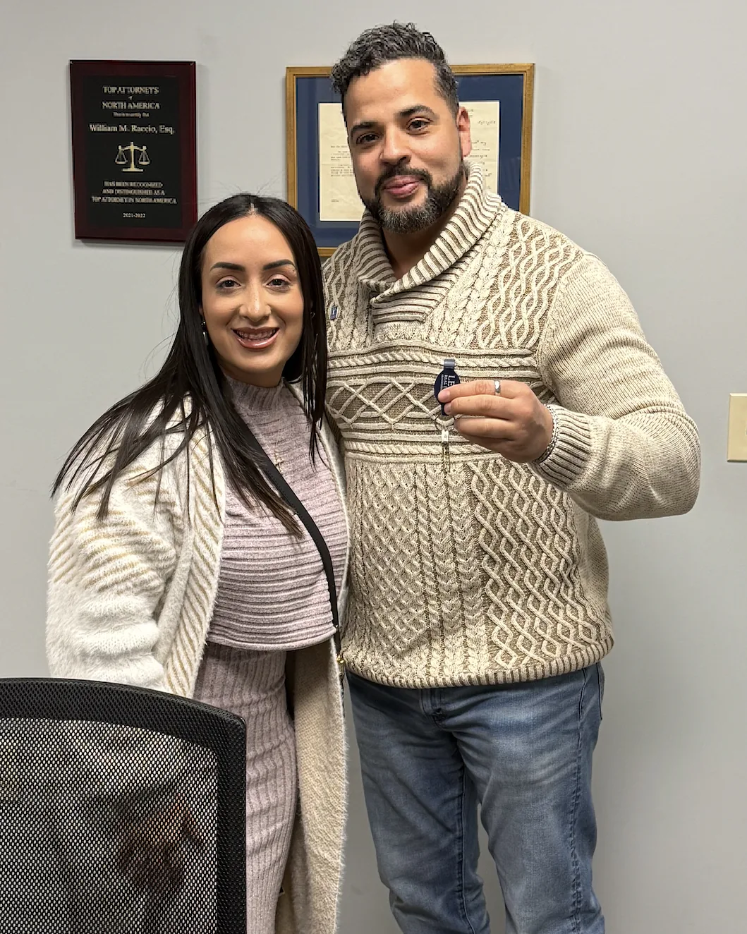 Nicholas with a client holding up the keys to her new home in the attorney's office.